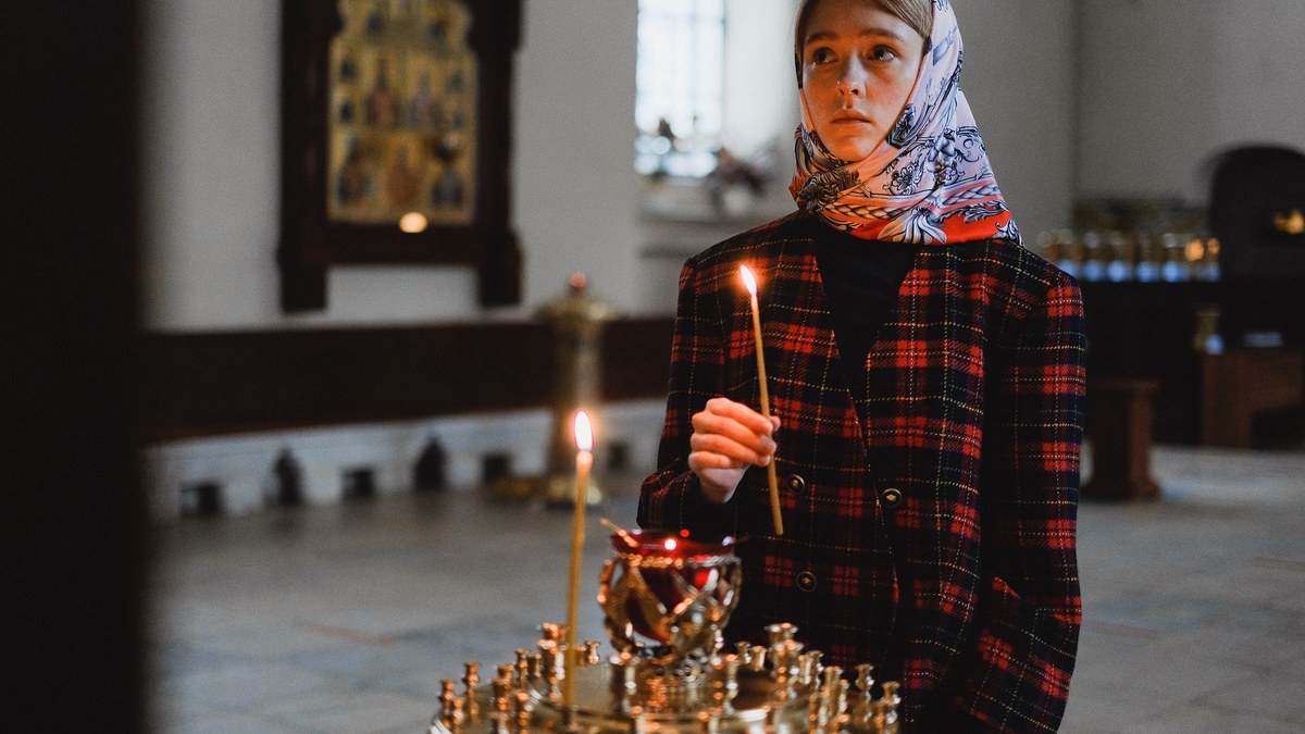 Посетител държи запалена свещ в храм